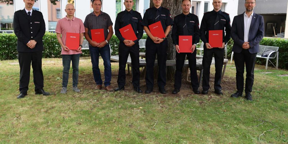 Feuerwehrmänner und OB schauen in die Kamera.