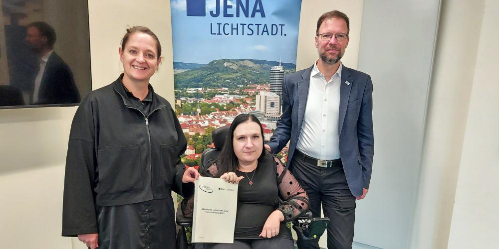 Drei Personen mit einer Broschüre