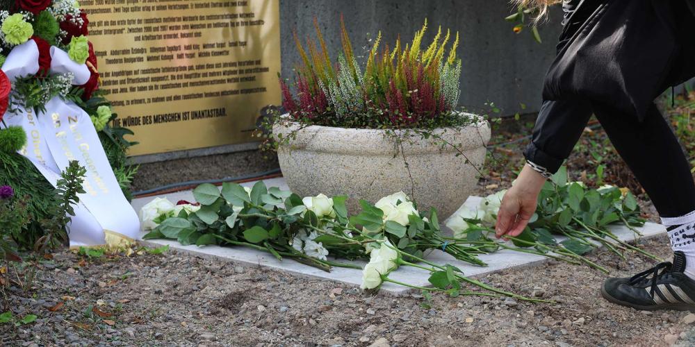 Frau legt Blume an Gedenkstelle ab