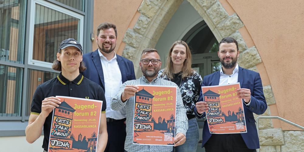 Fünf Personen halten drei Plakate in die Kamera.