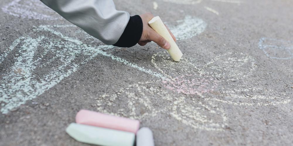 Kind, das mit Kreide auf die Straße zeichnet