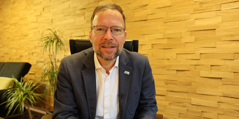 Ein Mann sitzt auf einem Stuhl und schaut in die Kamera