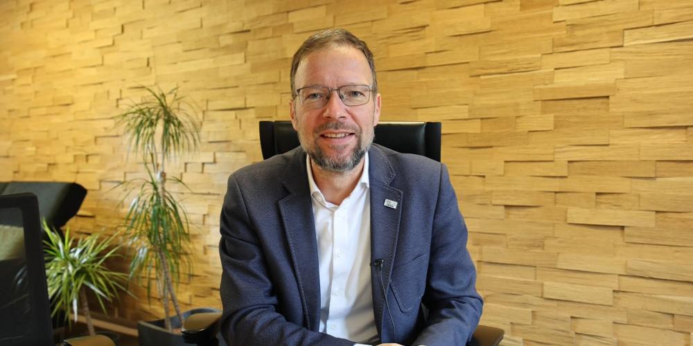 Ein Mann sitzt auf einem Stuhl und schaut in die Kamera