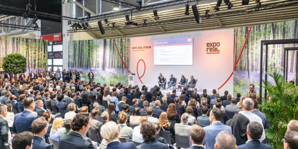Viele Menschen sitzen im Publikum und hören Podiumsdiskussion zu.