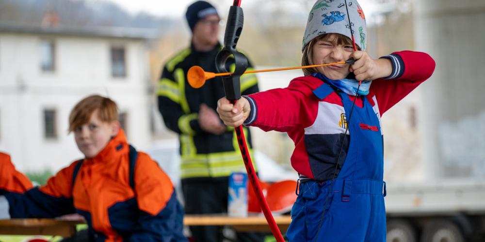 Kind schießt mit Pfeil und Bogen.