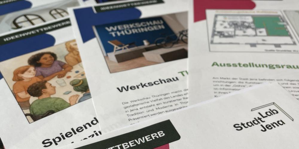 Auf einem Tisch liegen mehrere Broschüren zum Ideenwettbewerb 2025