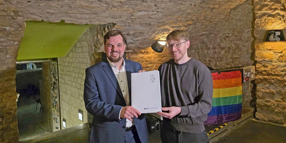 Zwei Personen halten ein Dokument in der Hand. 