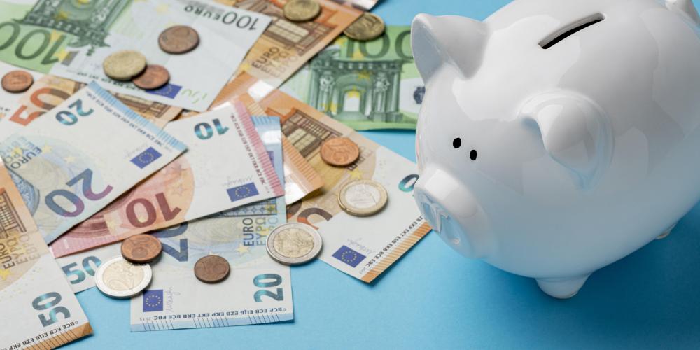 Bargeld liegt auf einer Fläche verteilt. Daneben steht ein Sparschwein.