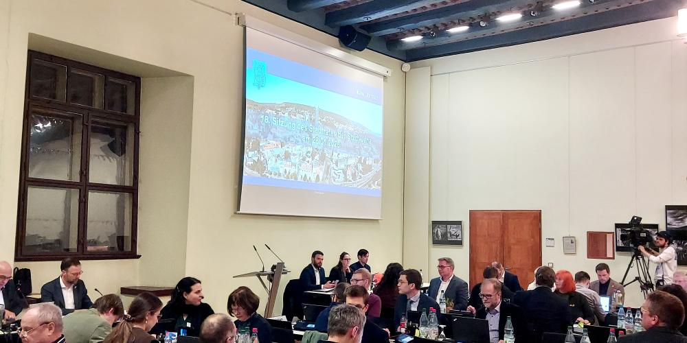 Stadtratsmitglieder im Historischen Rathaus sitzen an Tischen