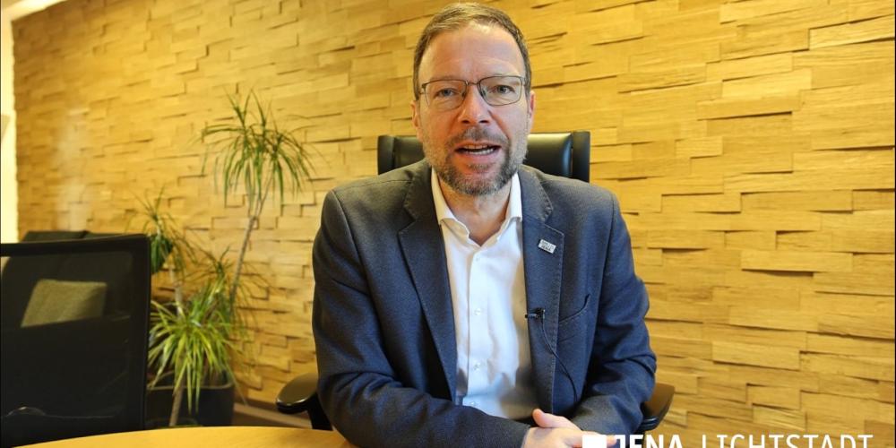 Ein Mann sitzt an einem Tisch und blickt in die Kamera.