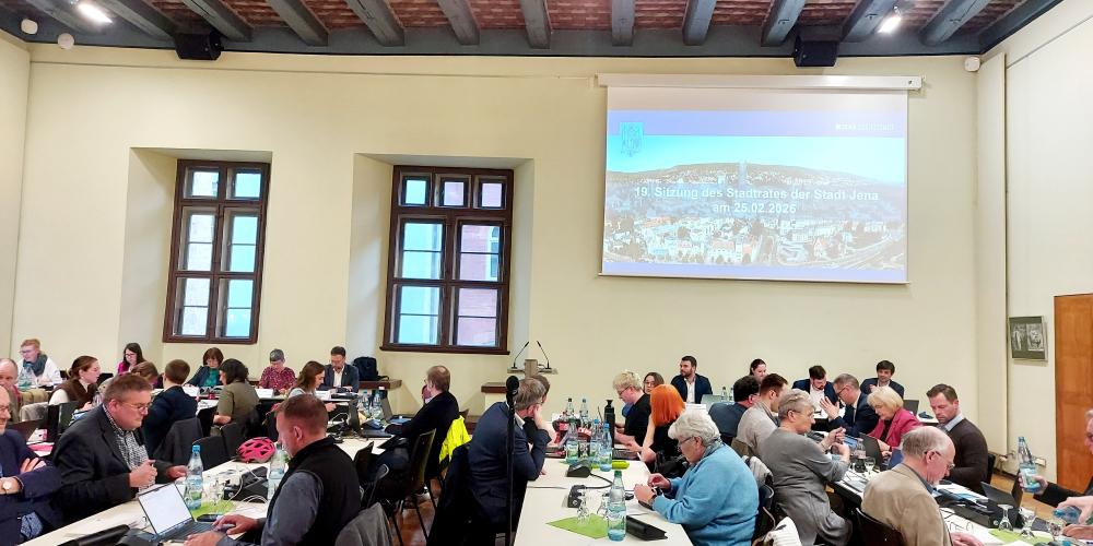 Stadtratsmitglieder sitzen an Tischen im Historischen Rathaus während der Stadtratssitzung