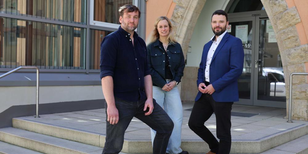 Drei Personen lächeln in die Kamera.