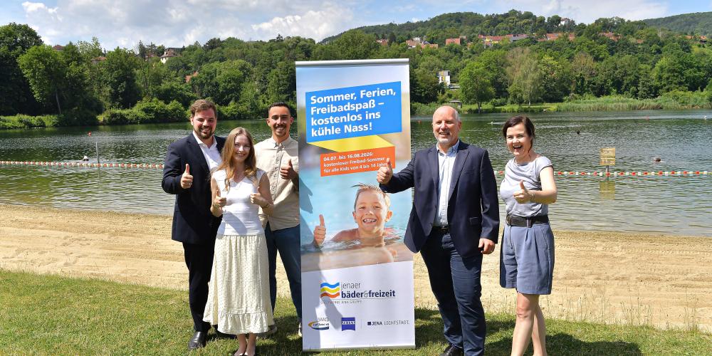 Fünf Menschen stehen an einem Badesee.
