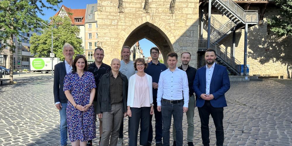 Gruppe von Menschen steht vor dem Johannistor in Jena und lächelt in die Kamera.