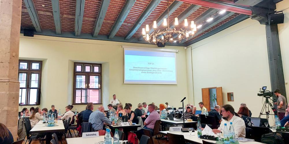 Stadtratsmitglieder sitzen an Tischen im Historischen Rathauses während der Stadtratssitzung