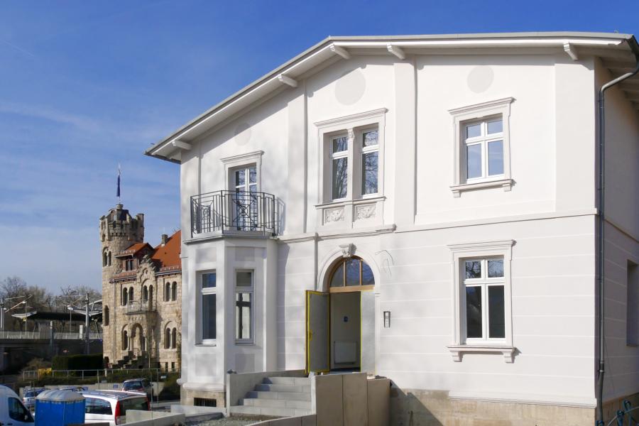 Ein weißes Haus im Hintergrund ein burgähnliches Gebäude