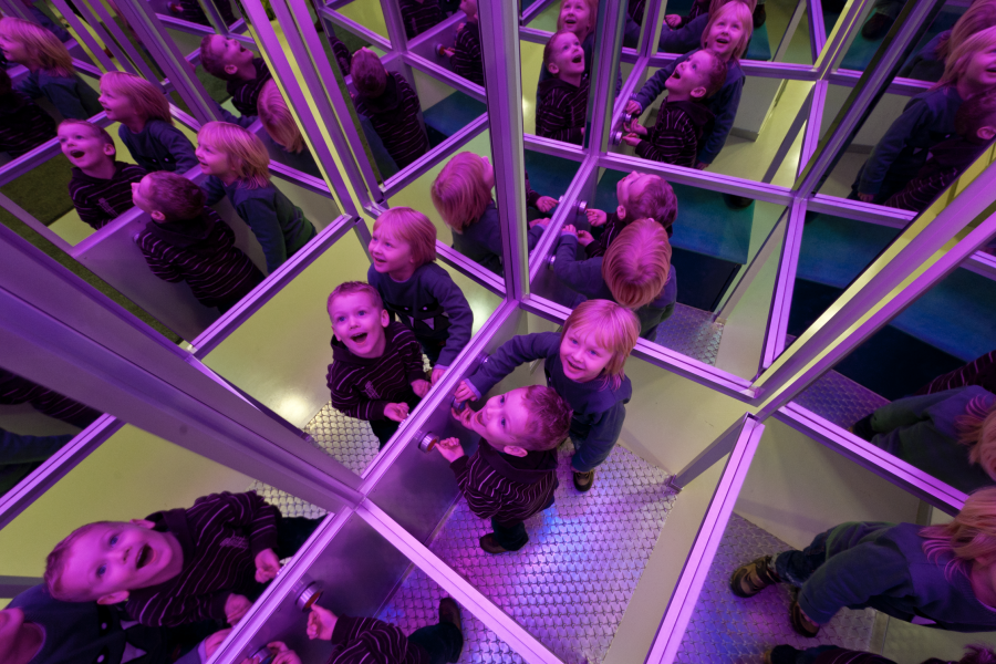 Eine Kindergruppe spiegelt sich in vielen Spiegeln wider