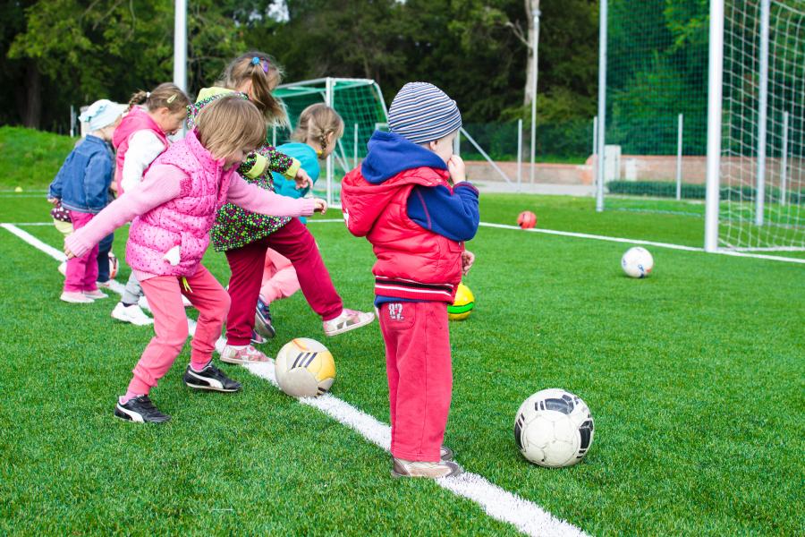 Kinder stehen vor einem Tor und schießen den Ball los