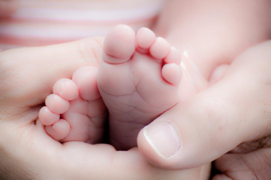 Eine erwachsene Hand umgreift liebevoll ein Babyfuß