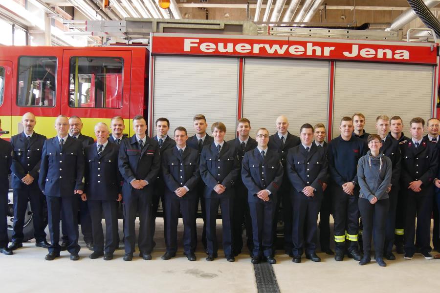 Eine Gruppe von Menschen in Uniformen vor einem Fahrzeug der Feuerwehr