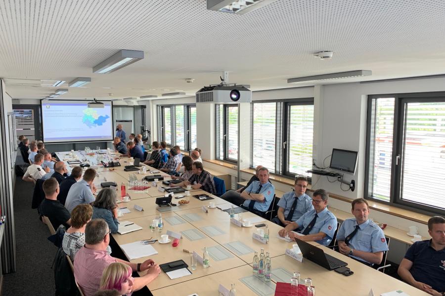 Eine Gruppe von Menschen verfolgt eine Präsentation auf einem Beamer