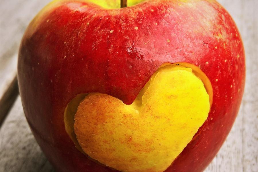 Ein Apfel mit einem Herz-Symbol auf einem Tisch liegend
