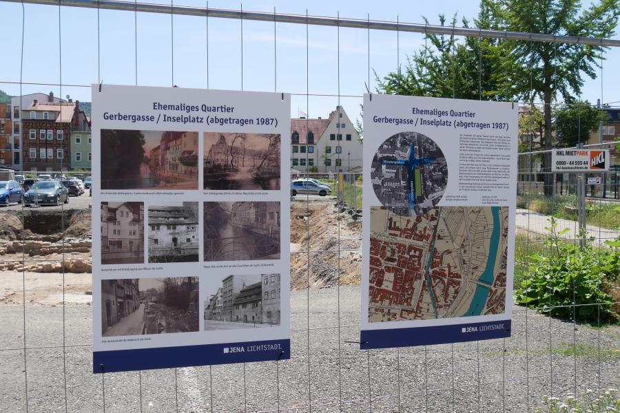 Zwei Informationstafeln an einem Bauzaun