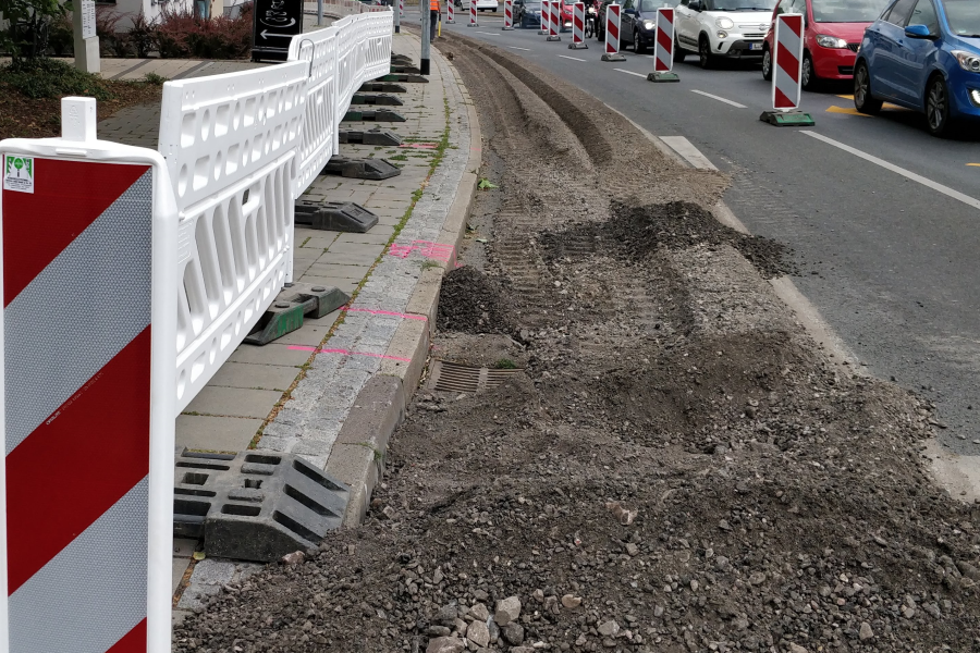 Der Abbeigestreifen einer mehrspurigen Straße ist wegen Bauarbeiten abgesperrt und der Asphalt aufgerissen. 