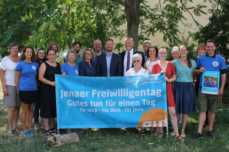 OB Nitzsche, Jenapharm-Geschäftsführer Gerber, zahlreiche Einsatzstellen und die Mitarbeiter der Freiwilligenagentur und Bürgerstiftung Jena halten ein Banner des Freiwilligentags.
