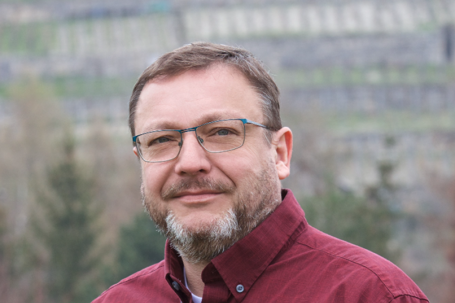 Ein Mann schaut in die Kamera, im Hintergrund Berge