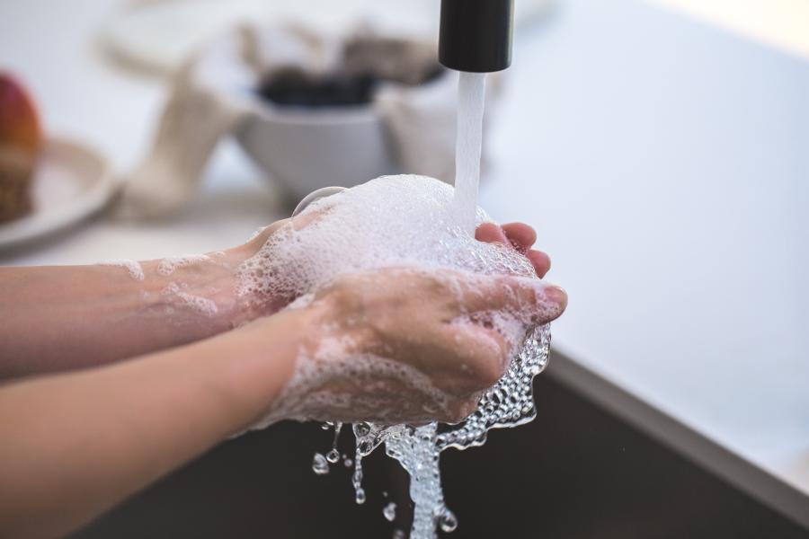 Eine Person wäscht sich seine Hände unter fleißendem Wasser, es schäumt