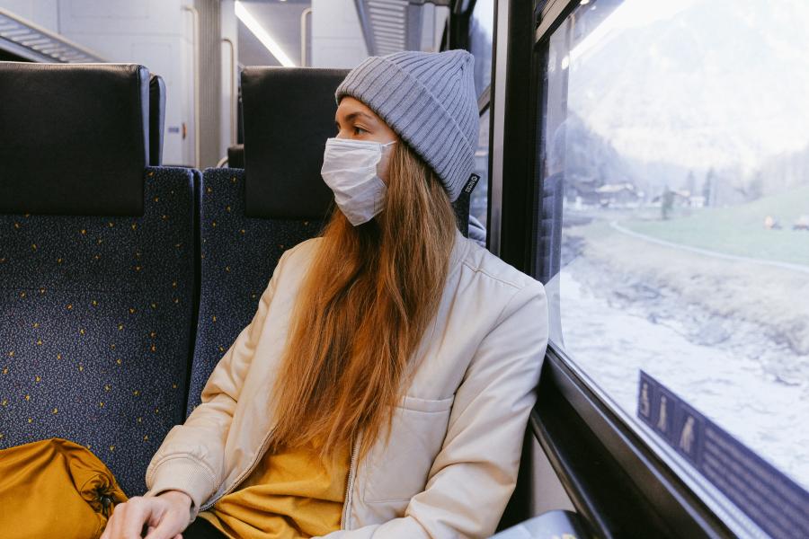 Faru sitzt in einer Bahn und trägt eine Nase-Mund-Bdeckung