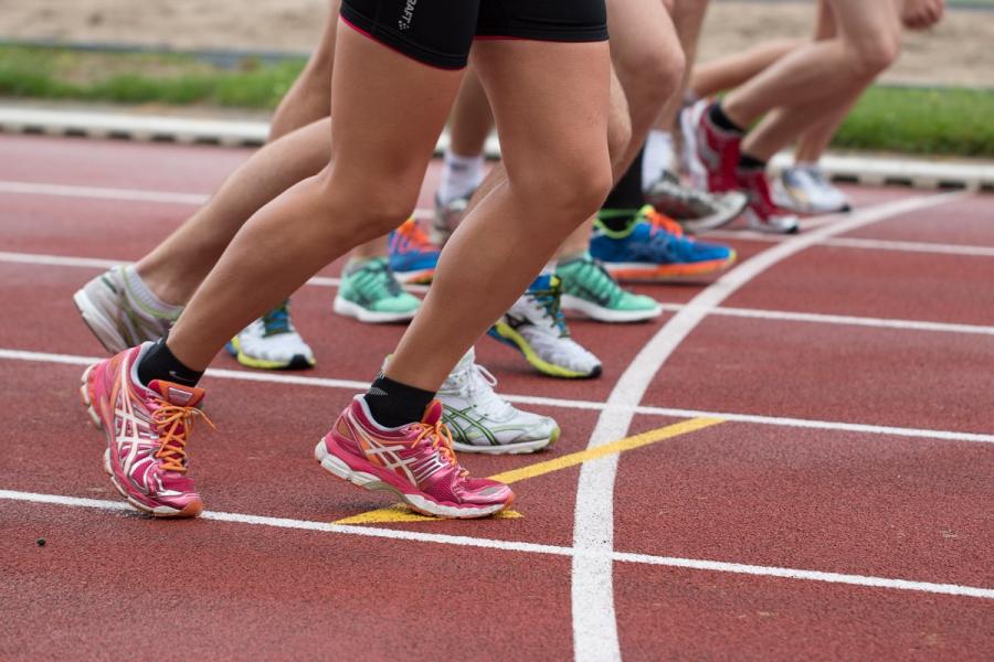 Die Beine mehrere Läufer mit Turnschuhen und kurzen Laufhosen auf einer Laufbahn in Startposition