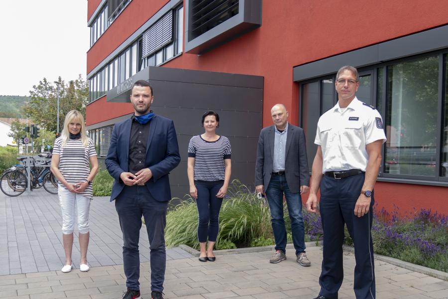 Fünf Menschen in einer Gruppe schauen in die Kamera