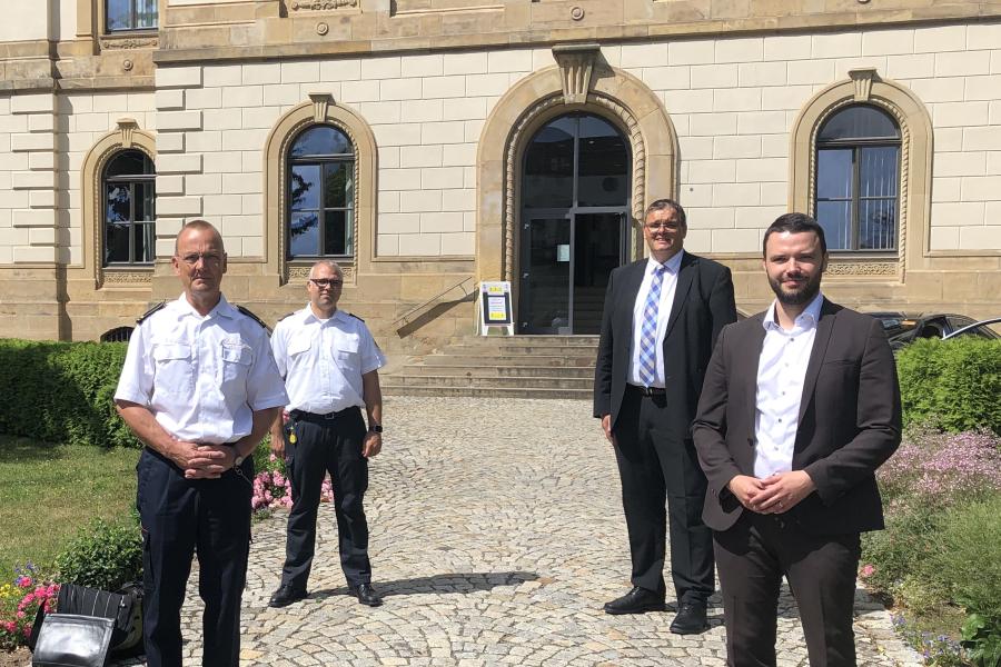 Vier Personen stehen vor einem Haus im Abstand von 1,5 m.