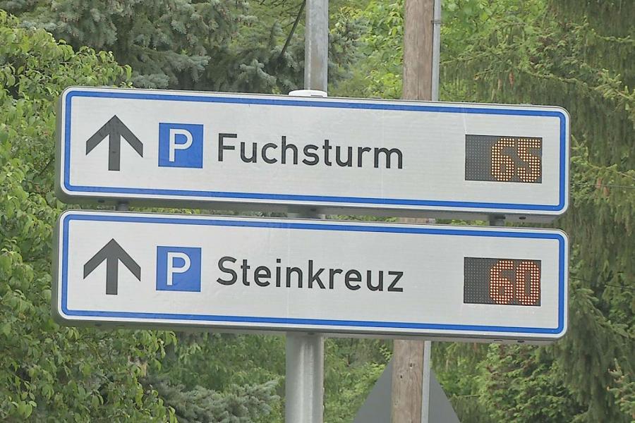 Zwei rechteckige weiße Schilder mit der Aufschrift Fuchsturm und Steinkreuz. Dahinter befindet sich die Digitalanzeige mit der Anzahl der freien Parkplätze.