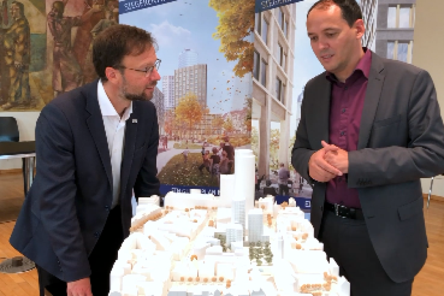 Zwei Personen diskutieren über ein Stadtmodell gebeugt