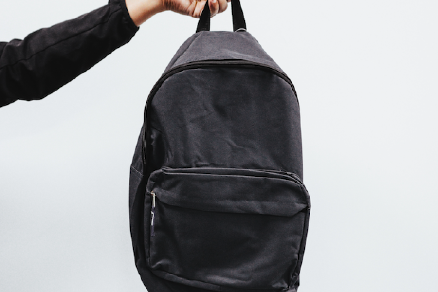 Eine Hand hält einen Rucksack in die Luft