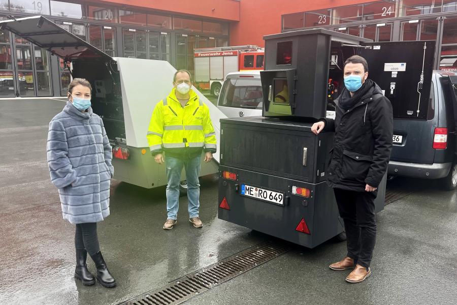 Drei Menschen mit Maske vor technischen Geräten