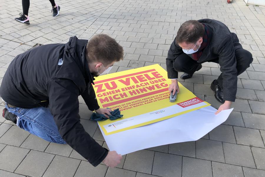 Zwei Menschen kleben einen Bodenaufkleber