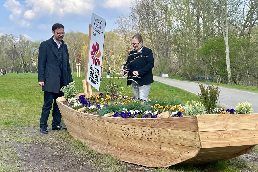 Zwei Menschen hinter einem Blumenbeet in Form eines Bootes