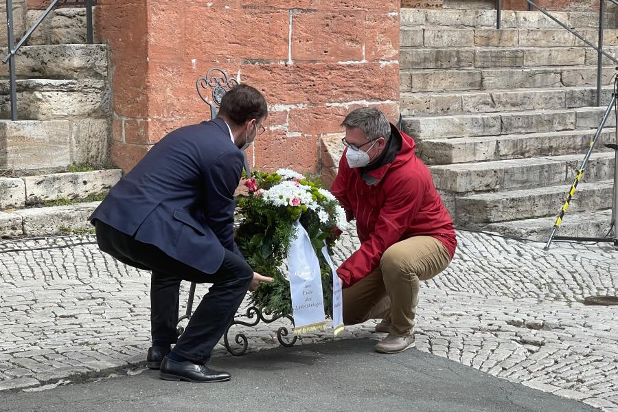Zwei Männer legen einen Kranz nieder
