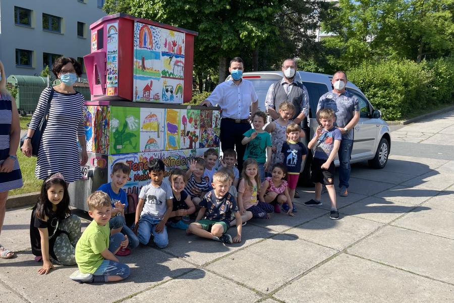 Kinder und Erwachsenen stehen vor einem bunt bemalten Gerät
