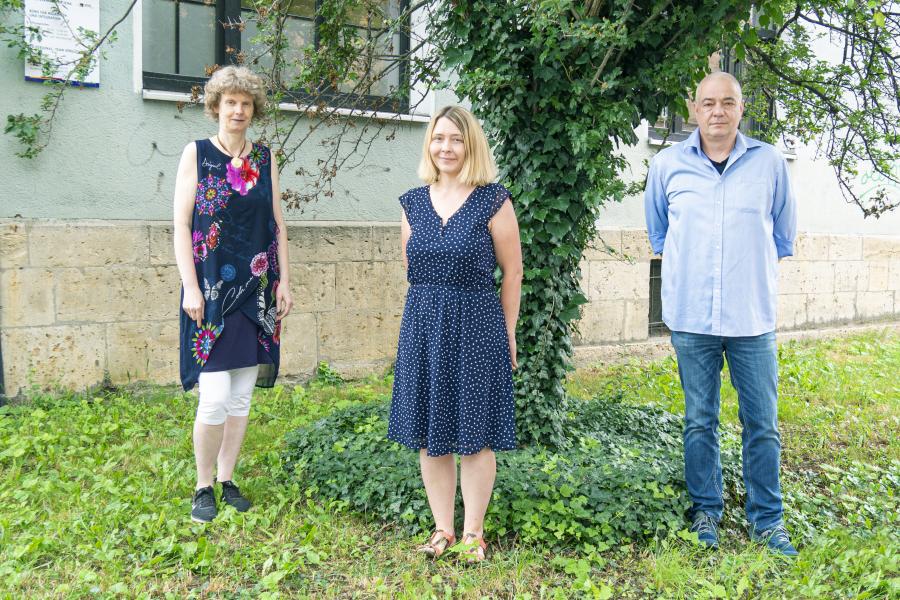 Drei Menschen – zwei Frauen und eine Mann –stehen auf eine Wiese und schauen in die Kamera 