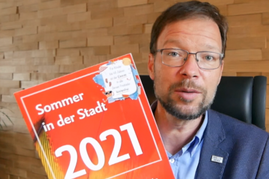 Ein Mann hält eine Broschüre in die Kamera