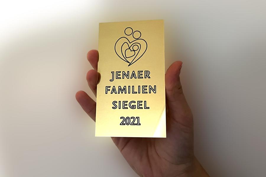 Eine Hand hält eine goldfarbene Tafel in die Kamera