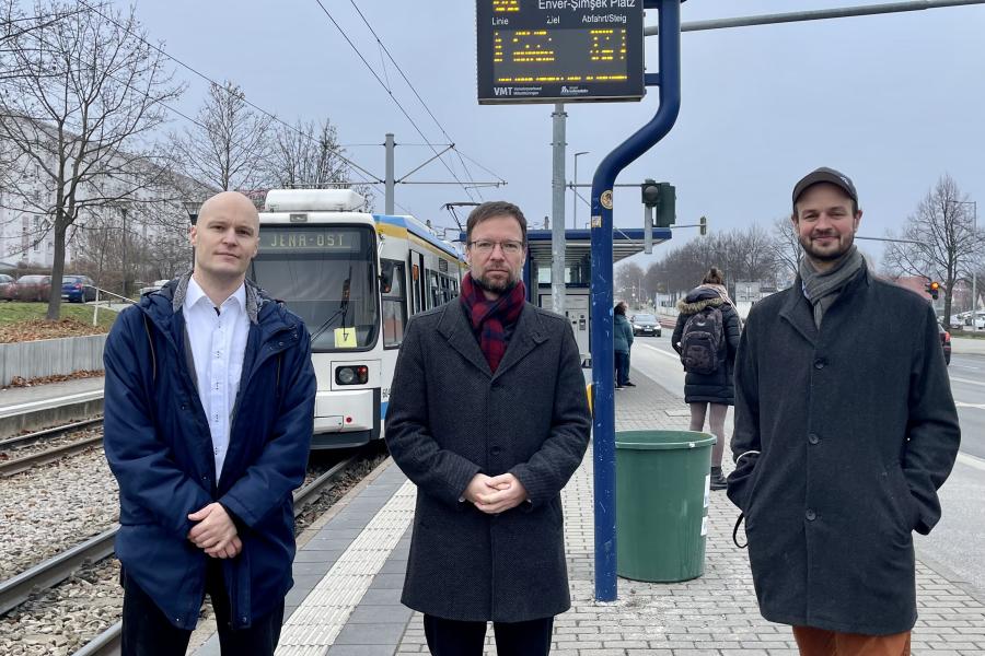 Drei Männer an einer Haltestelle
