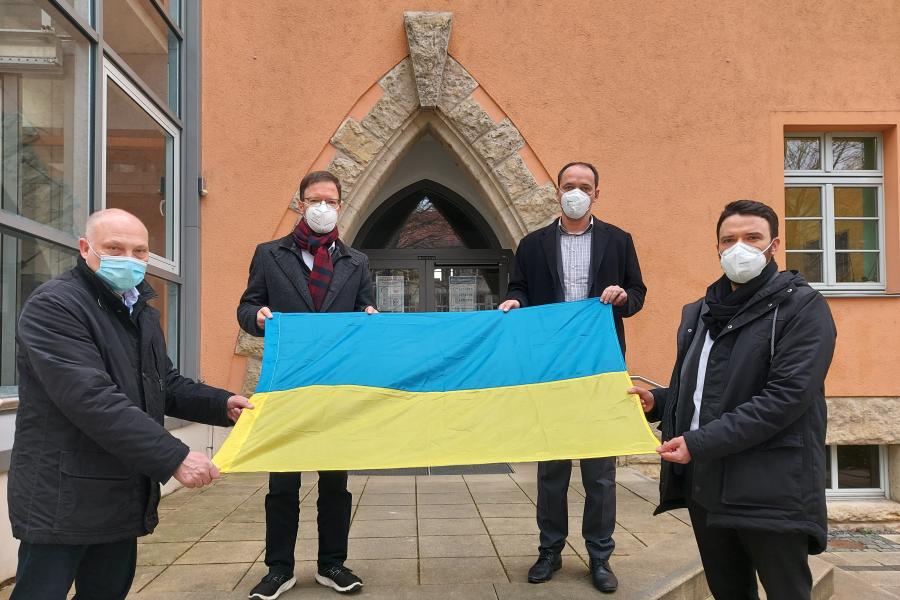 Vier Männer halten eine Fahne