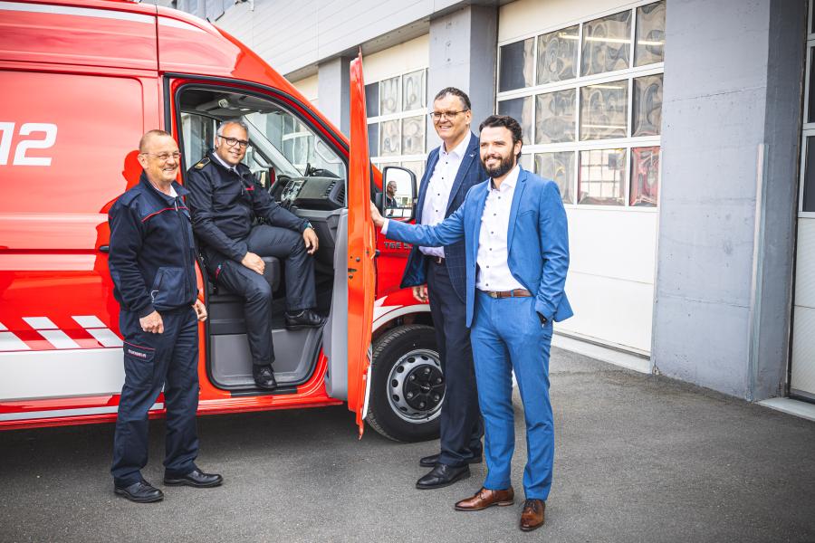 Vier Menschen an einem Feuerwehrwagen