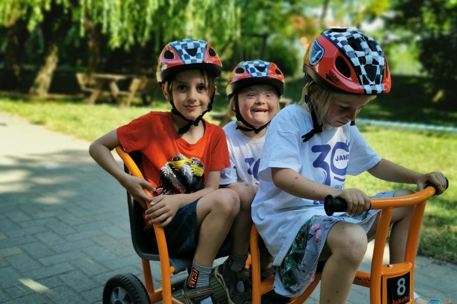 Drei Kinder auf einem Tretfahrzeug